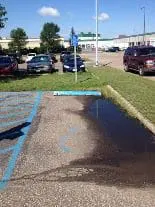 A handicap parking space that isn't level and with faded paint.