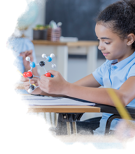Picture of a child in school holding a model of molecules.