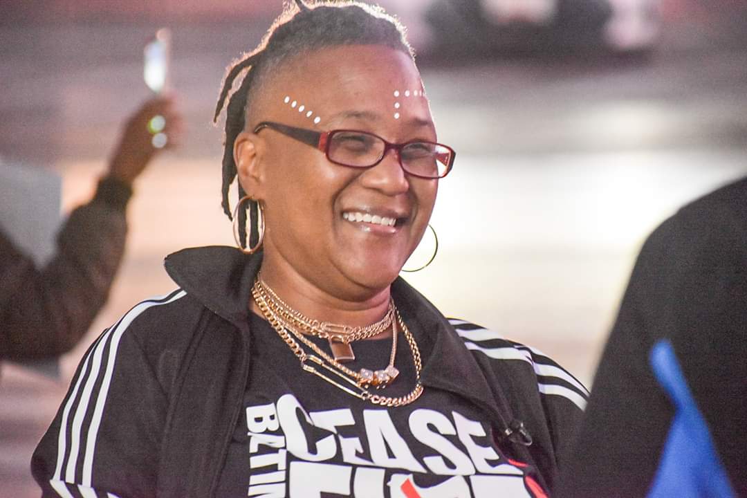 Erricka smiles to someone off camera, she is smiling, wearing a Baltimore Ceasefire 365 shirt