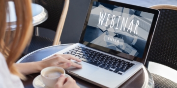 Woman sitting at laptop with screen that says webinar