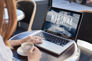 Woman sitting at laptop with screen that says webinar