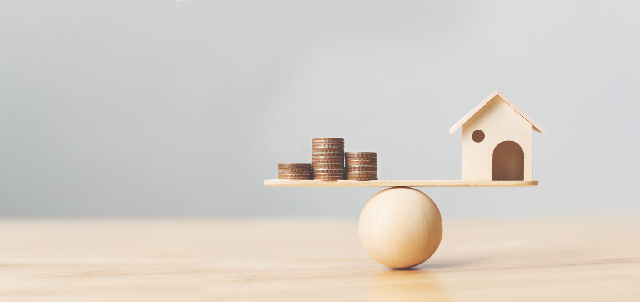 Wooden home and money coins stack on wood scale.