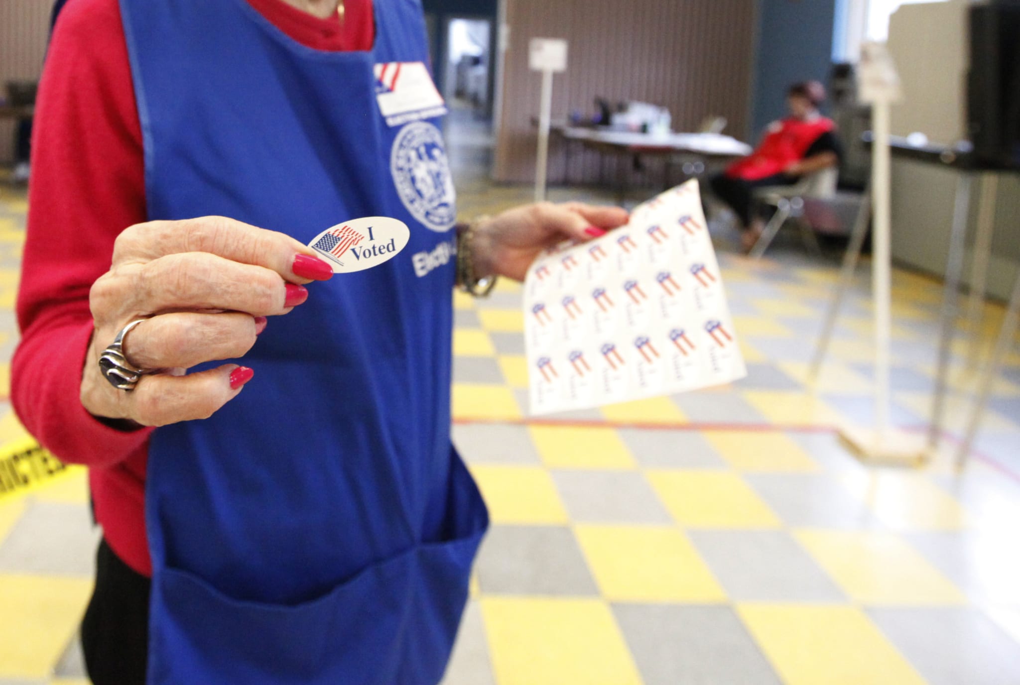 Woman with long red nails holding a I voted sticker