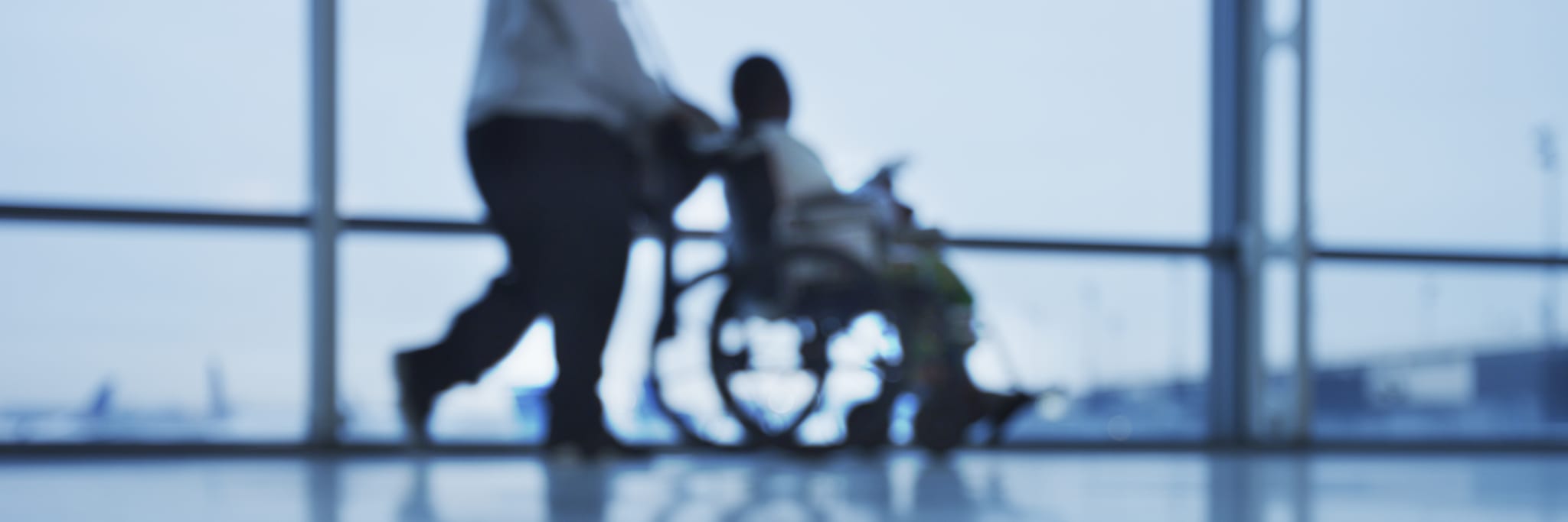 person in wheelchair at aiport is assisted by person