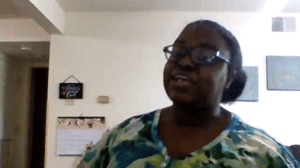 Ruqayyah, an African American woman, wears glasses and sits in her room