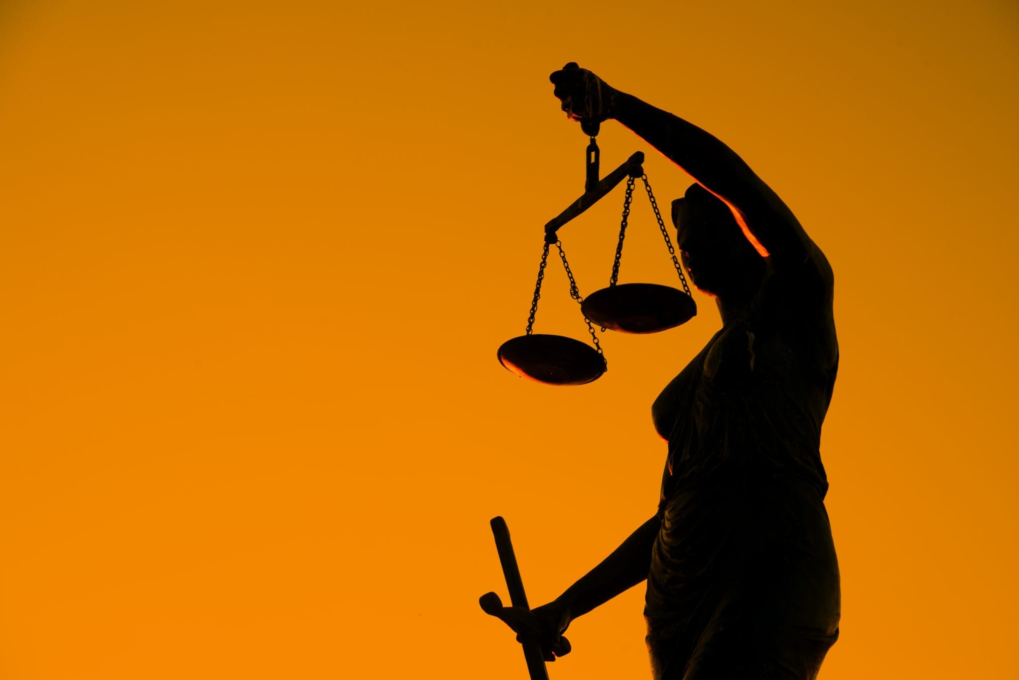 Statue holding scales of justice on an orange background