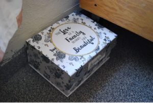 A card box on a floor that reads "The Love of a Family Makes Life Beautiful"