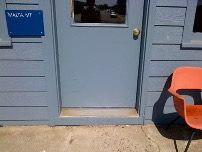Entrance to a train station. It's painted a faded blue and there's a bright orange chair outside. 