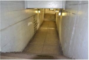 A dimly lit tunnel with stairs present and no ramp access.