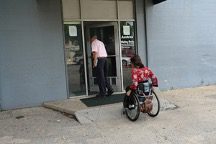 A wheelchair user going up a steep ramp to under a statio