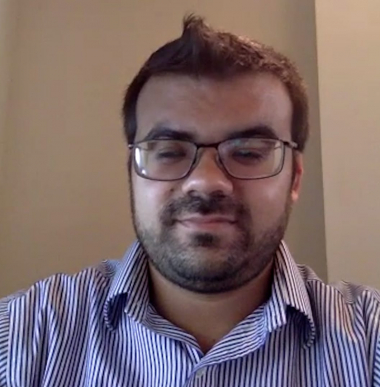 A male with brown hair and glasses smiles to the camera.
