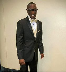 Image of Wilbert Johnson. He is wearing a tuxedo and smiling at the camera.